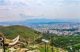 پارک جمشیدیه تهران؛ منظره پارک از بالا که مشرف به تپه‌هایی سرسبز و نمایی از شهر است. 